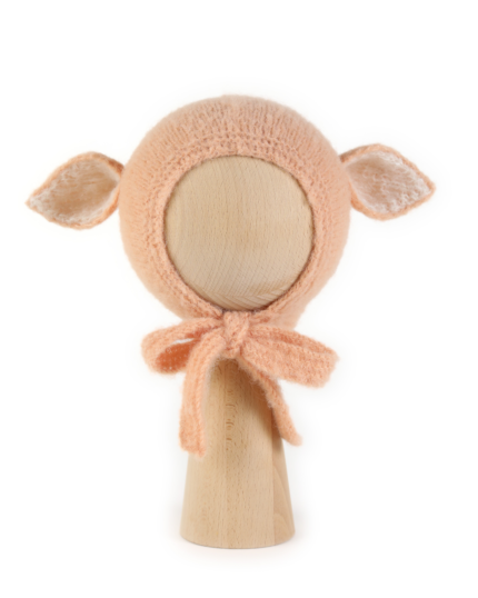 A handmade hat with ears in a pastel orange color displayed on a mannequin.