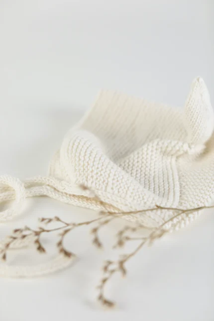 A handmade hat with pointed ears in a delicate white color displayed on a side.